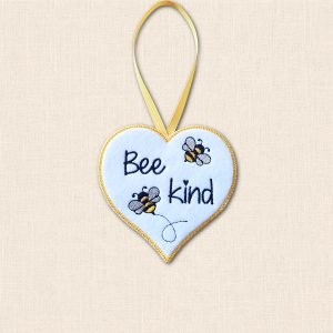 White felt 'Bee Kind' heart hanger with two embroidered bees, golden yellow stitched edging and a matching ribbon loop.