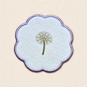 White embroidered Dandelion Candle Coaster featuring a delicate dandelion seed head, subtle stitched background pattern and purple scalloped border.