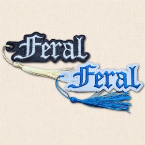 Black and white embroidered 'Feral' bookmarks displayed together with cream and blue tassels.