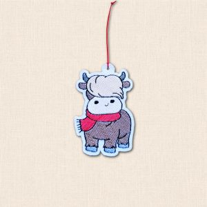 Embroidered felt Highland cow Christmas ornament with a brown body, cream fringe, red scarf and red hanging cord.