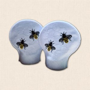 Pair of white felt LED tealight covers featuring golden yellow and black embroidered bees with subtle honeycomb stitching.