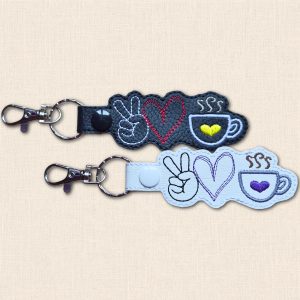 Black and white faux leather coffee keyrings with embroidered peace sign hands, hearts and steaming coffee cups, each with a split ring and lobster clasp.