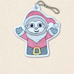Smiling embroidered felt sloth wearing a red Santa hat and suit, with open arms and a metal ball chain, on cream fabric.